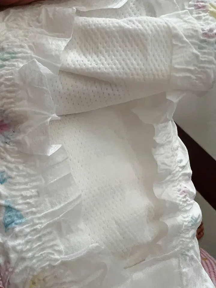 Cận cảnh mặt trong miếng tã dán Bobby size M, lớp mặt trắng có nhiều hàng lỗ thấm nhỏ và vách chống tràn nhăn hai bên