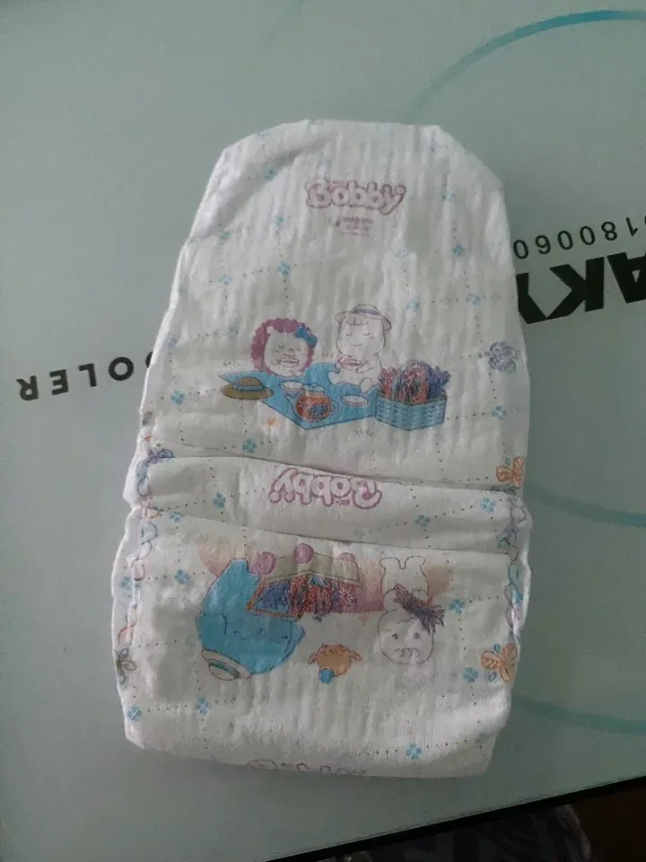 Mặt ngoài miếng tã dán Bobby size XL màu trắng, logo Bobby màu hồng và họa tiết hoạt hình