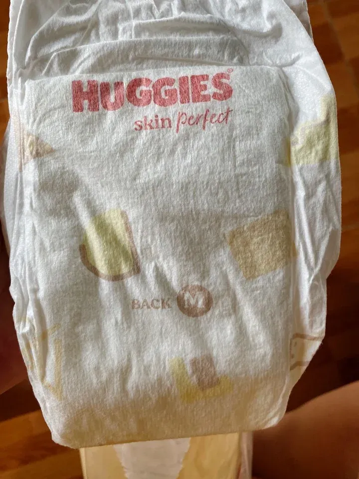 Mặt lưng miếng tã dán Huggies Skin Perfect size M màu trắng, logo đỏ và chữ BACK M